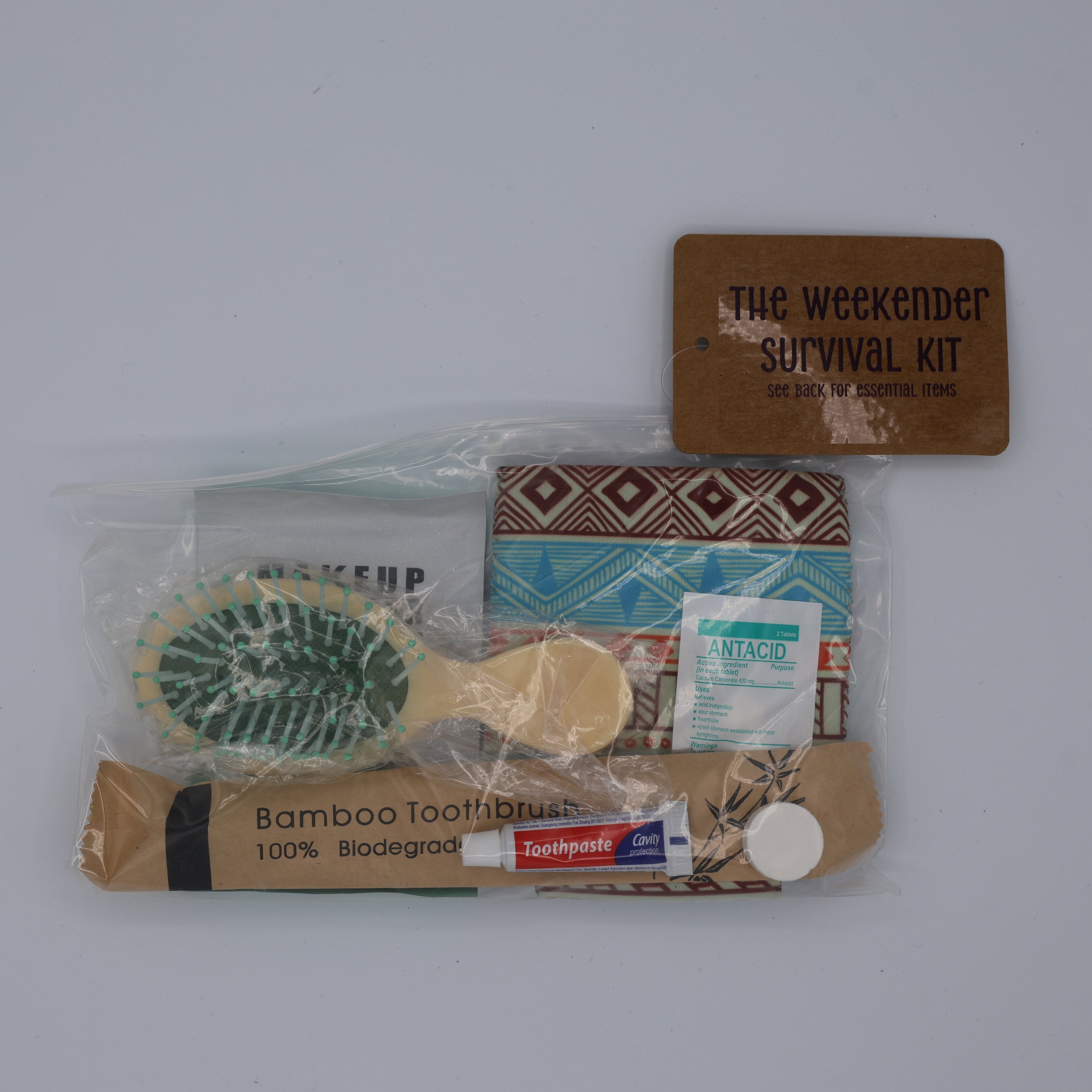 Weekender survival kit with various items including a hairbrush, toothbrush, toothpaste, antacid, ect.